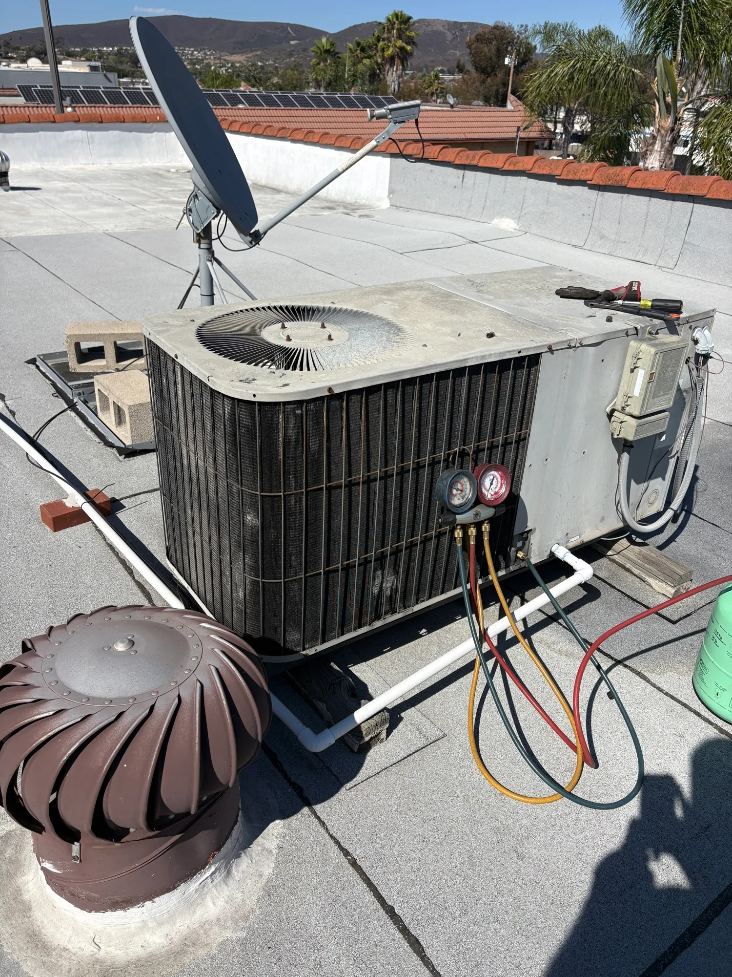 Abundant Air technician diagnosing rooftop HVAC unit with gauges